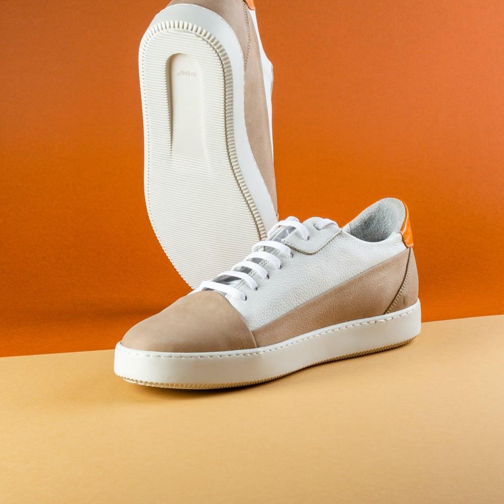 Front shot of the product, white sneakers on orange background